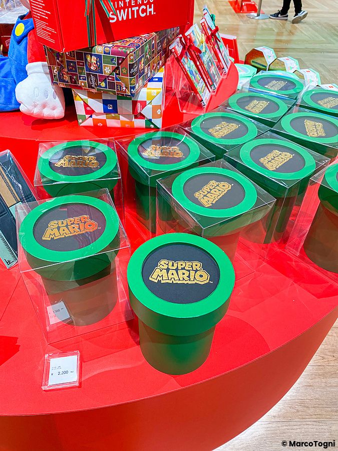 Contenitori a forma di tubo di Super Mario esposti in vendita su un tavolo rosso nel Nintendo Store a Tokyo.