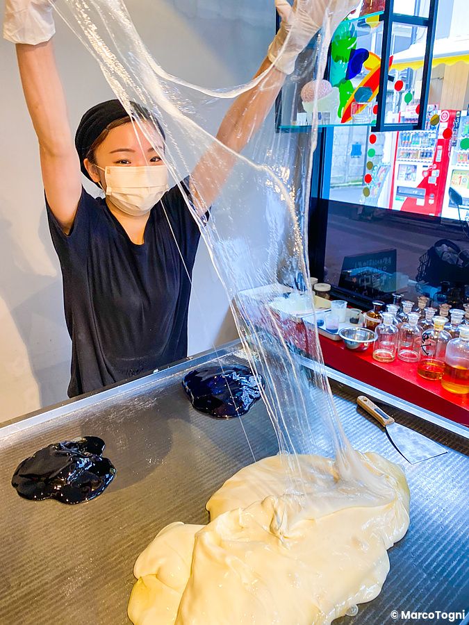 Una donna con mascherina stira a mano un impasto di zucchero durante la preparazione caramelle a Papabubble.