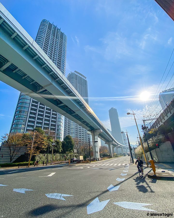Strada urbana nel quartiere italiano a Tokyo con viadotto e grattacieli.