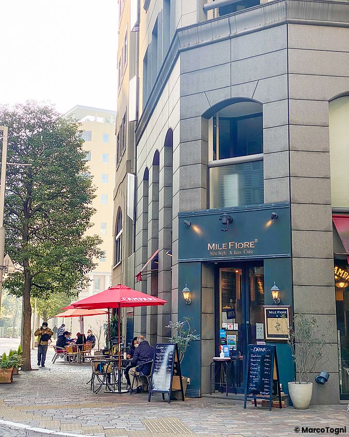 Un caffè all'aperto nel quartiere italiano di Tokyo con ombrelloni rossi.