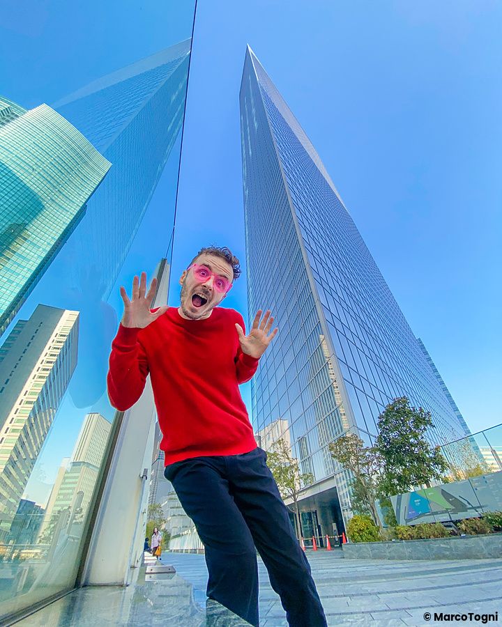Marco Togni con maglia rossa davanti al grattacielo Dentsu a Tokyo.