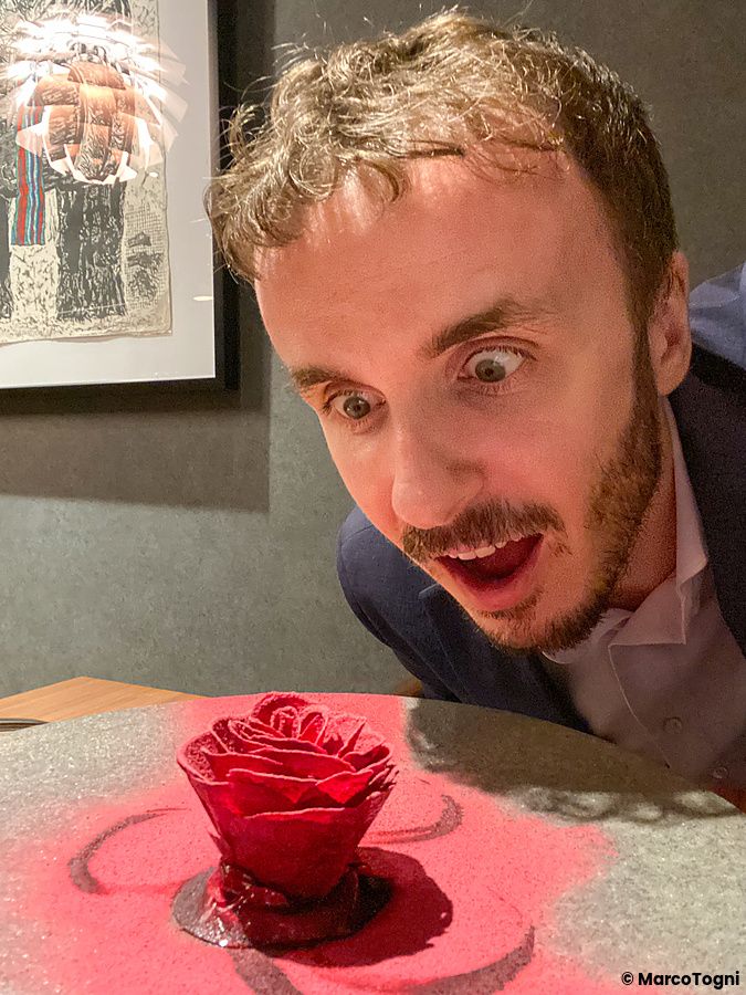 Marco Togni osserva il piatto iconico di Le Sputnik: una rosa di chips di barbabietola con foie gras, mango e kumquat.