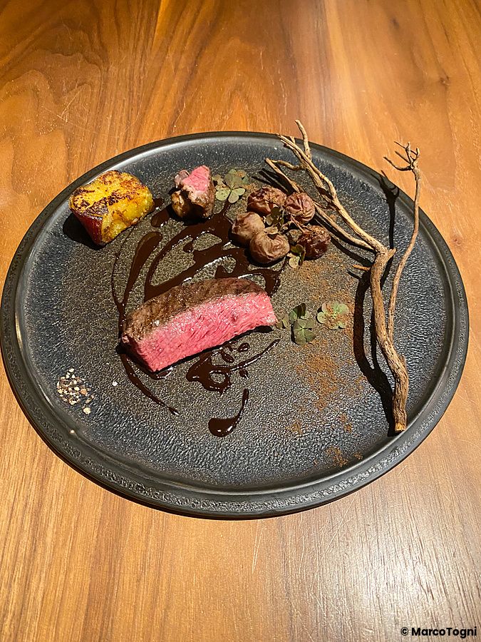 Carne di cervo con spezie, dolce uva passa e patata dolce presentata su un piatto scuro al ristorante Le Sputnik.