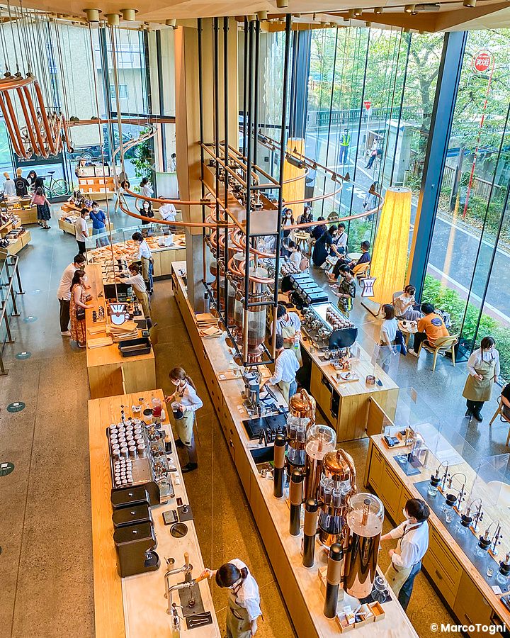 Veduta dall'alto dell'interno dello Starbucks Reserve a Naka-Meguro con persone ai tavoli e banconi di preparazione.