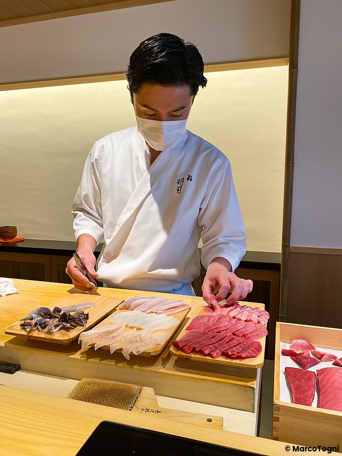 Chef prepara sushi su tovagliette di legno in un ristorante giapponese.