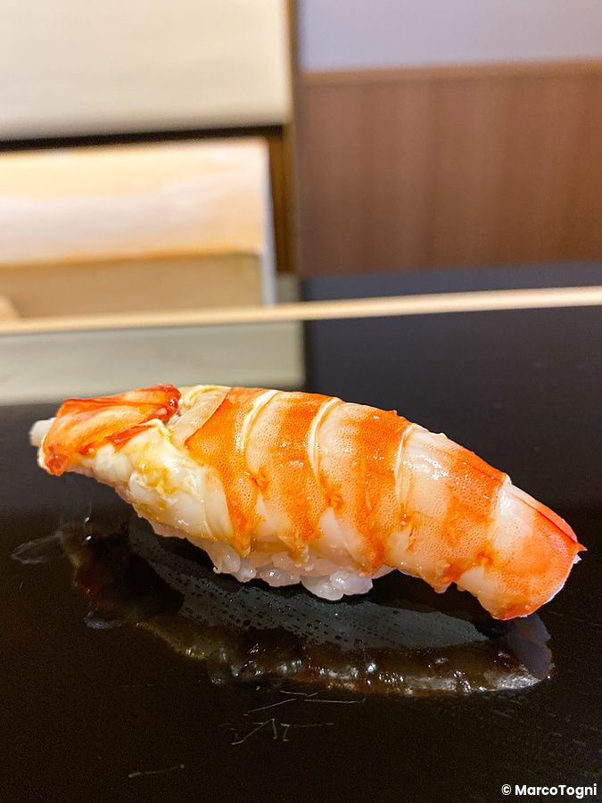 Nigiri di kuruma ebi su piatto nero lucido.