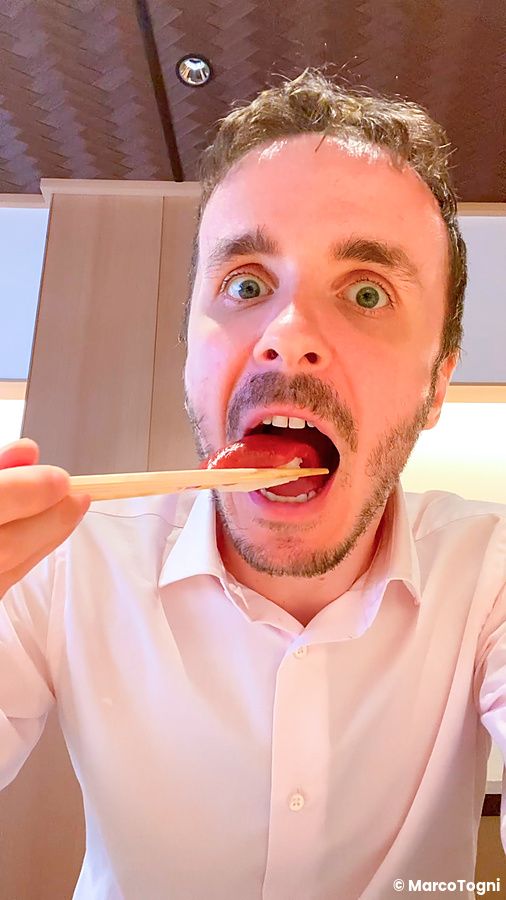 Marco Togni mangia sushi con bacchette in un ristorante a Tokyo.