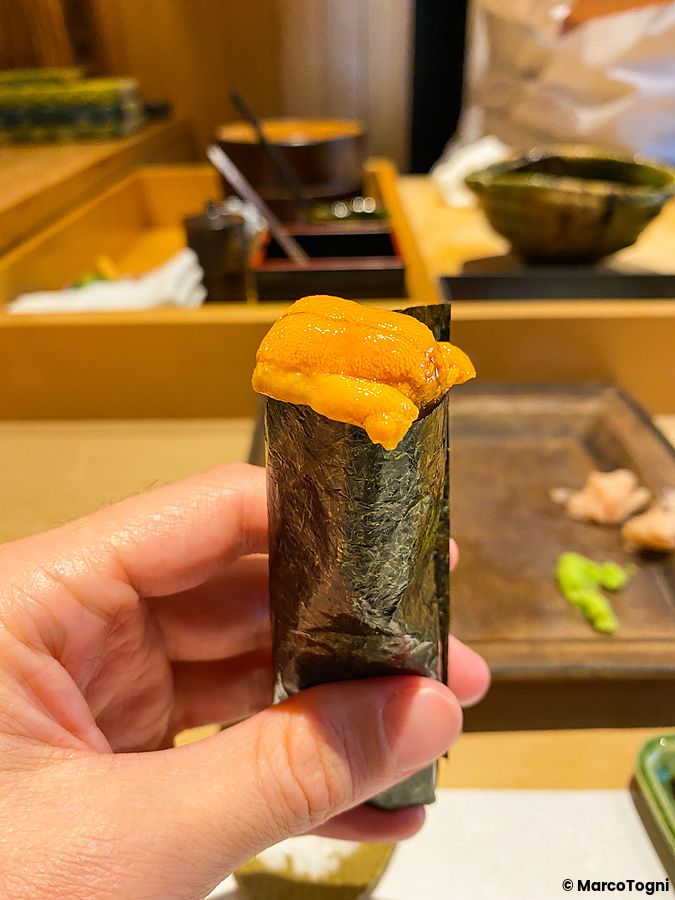 Maki con riccio di mare tenuto in mano da Sushi Takeuchi.