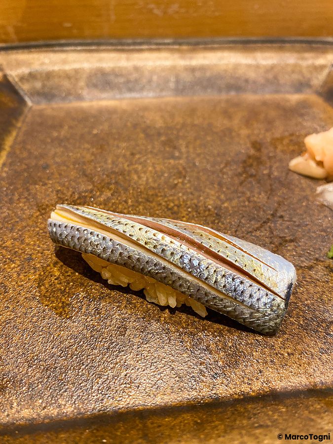 Un nigiri di kohada servito su un piatto scuro da Sushi Takeuchi a Tokyo.