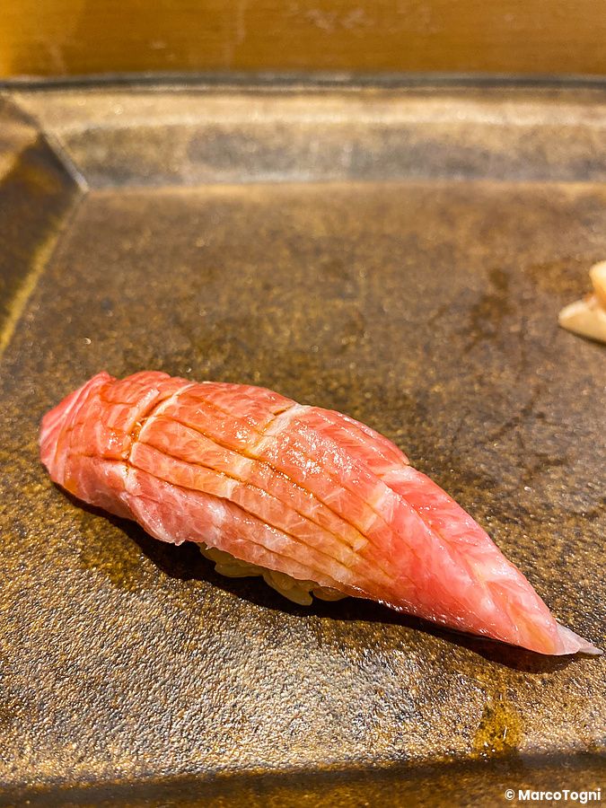 Un nigiri di otoro servito su un vassoio scuro presso Sushi Takeuchi.