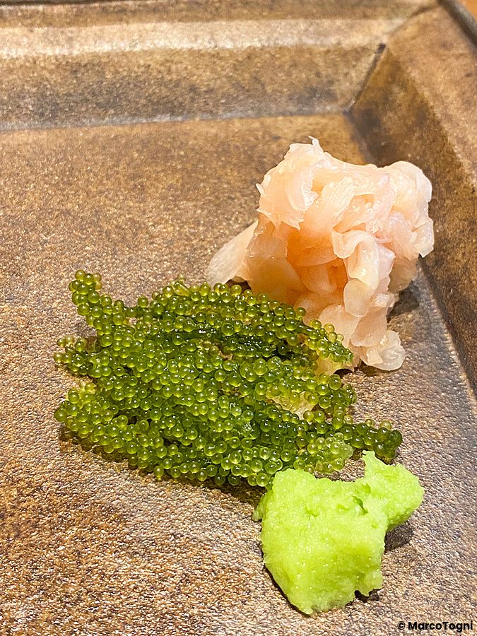 Nigiri di uva di mare con zenzero e wasabi servito su un piatto di ceramica da Sushi Takeuchi a Tokyo.