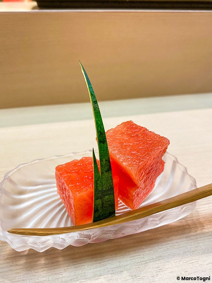 Cubetti di anguria fresca serviti su un piatto di vetro con una decorazione di scorza da Sushi Tou a Tokyo.