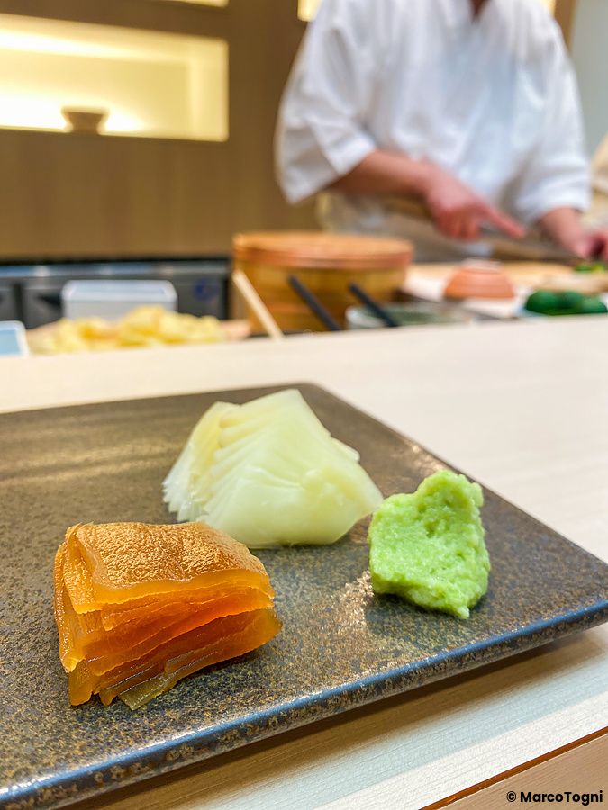 Un piatto con kampyo, zenzero e wasabi servito su un bancone di legno da Sushi Tou.