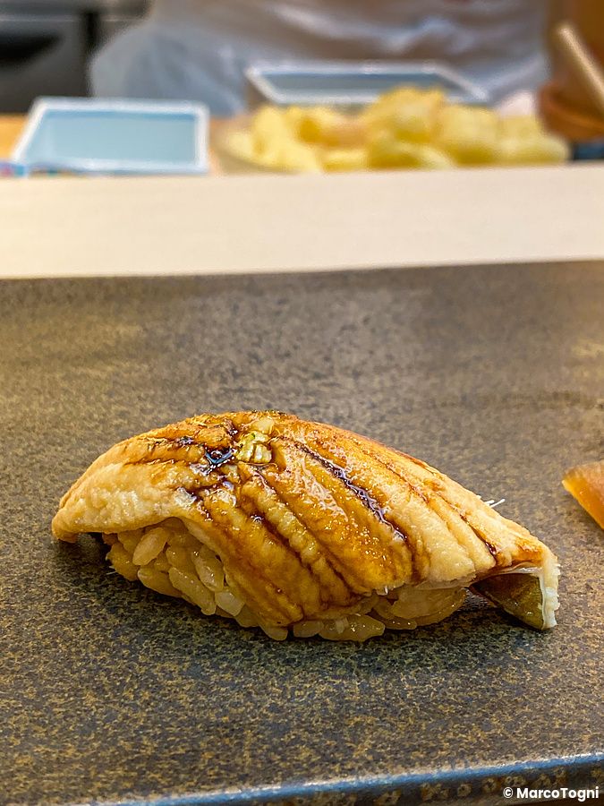 Un nigiri di anago servito su un piatto di pietra scura presso il ristorante Sushi Tou a Tokyo.
