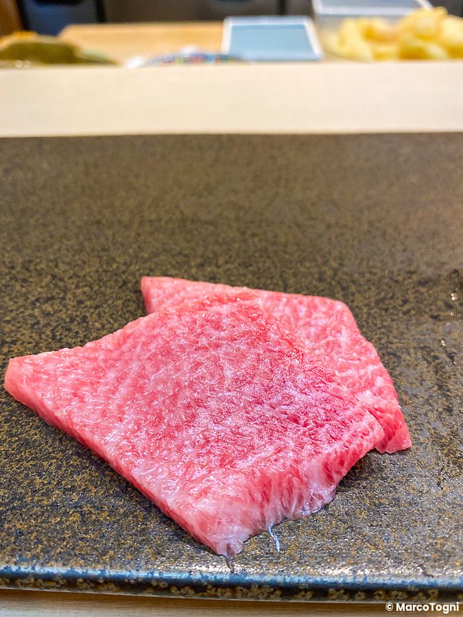 Due fette di tonno chutoro adagiate su un piatto di pietra scura presso da Sushi Tou.