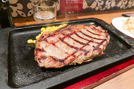 Bistecca di manzo grigliata servita su una piastra calda con mais in un ristorante Steak Lodge.