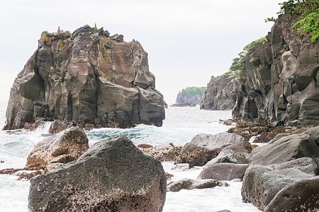 Veduta panoramica della Costa di Jogasaki in Giappone, con alte scogliere vulcaniche scure circondate dall'oceano.