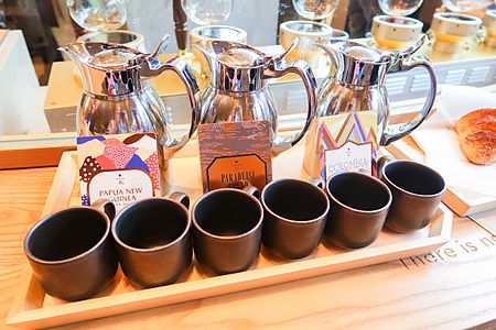 Tre caraffe metalliche e tazzine scure su un vassoio di legno durante una degustazione di caffè al Starbucks Reserve.