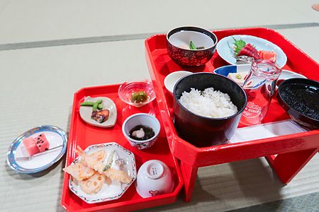 Un pasto tradizionale giapponese servito su vassoi rossi poggiati su un tatami presso il Tempio Gyokuzoin a Nara.