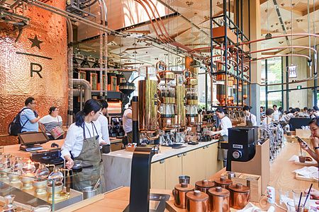 Interno dello Starbucks Reserve a Nakameguro, Tokyo, con baristi in uniforme e macchinari in rame per il caffè.