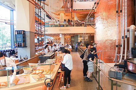 Interno dello Starbucks Reserve Roastery a Nakameguro con grandi tubi in rame, banconi e persone che visitano lo spazio.