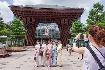 persone in kimono davanti alla stazione di Kanazawa con un fotografo