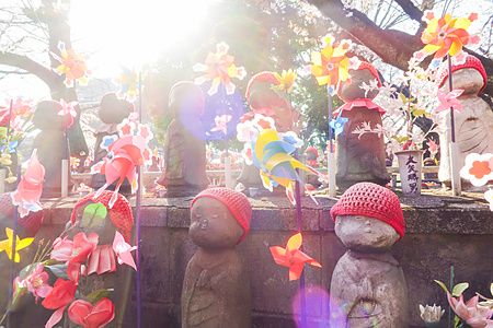 Statues of Jizō with red hats and colorful pinwheels at Zojoji Temple, Tokyo.