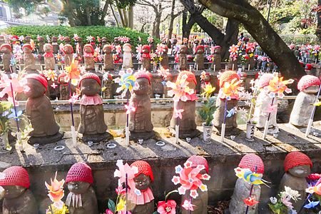 Statuine di Jizō con cappellini e mulinelli colorati al tempio Zojoji di Tokyo.