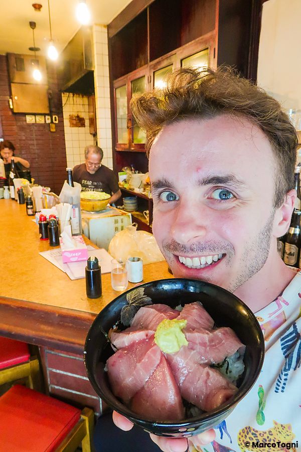 Marco Togni sorridente tiene in mano una ciotola di tonno all'interno del ristorante Maguro Koya a Nara.