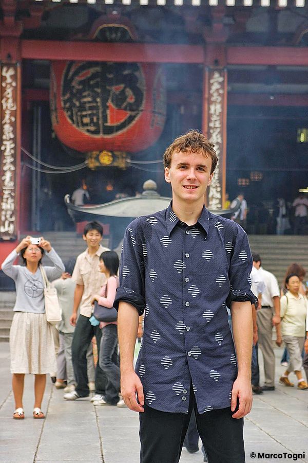 Marco Togni in primo piano con una camicia scura posa davanti alla grande lanterna rossa del tempio Senso-ji ad Asakusa.