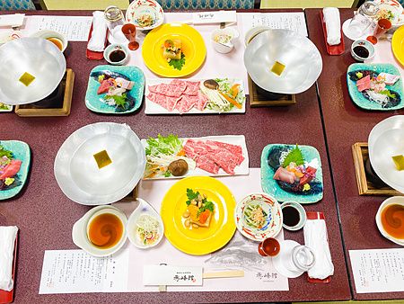 Tavolo apparecchiato con piatti tradizionali giapponesi durante una cena in ryokan.