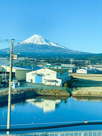Vista del Monte Fuji dal treno shinkansen con edifici in primo piano.