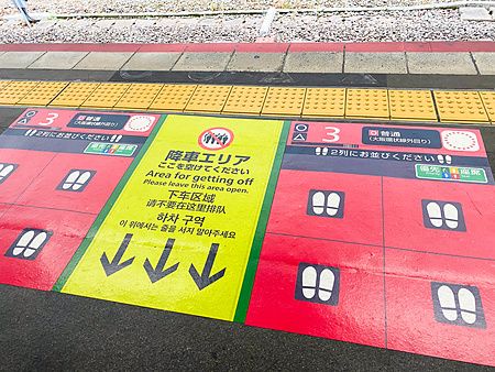 Segnaletica colorata sul pavimento di una stazione a Osaka per regolare la coda per prendere il treno in Giappone.