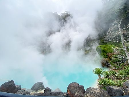 Veduta panoramica dell'Umi Jigoku a Beppu con la sua caratteristica acqua turchese circondata da denso vapore bianco.