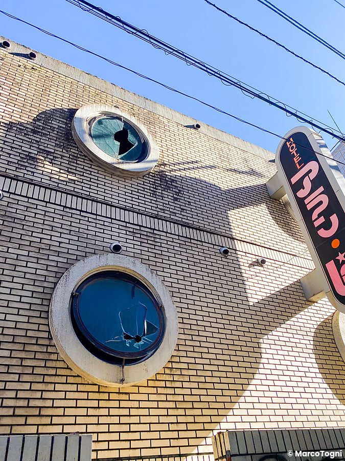 Facciata di un love hotel abbandonato a Shibuya con finestre rotte.