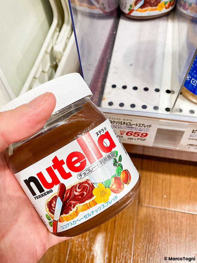 Una mano tiene un barattolo di Nutella tra gli scaffali del negozio Seijo Ishii.