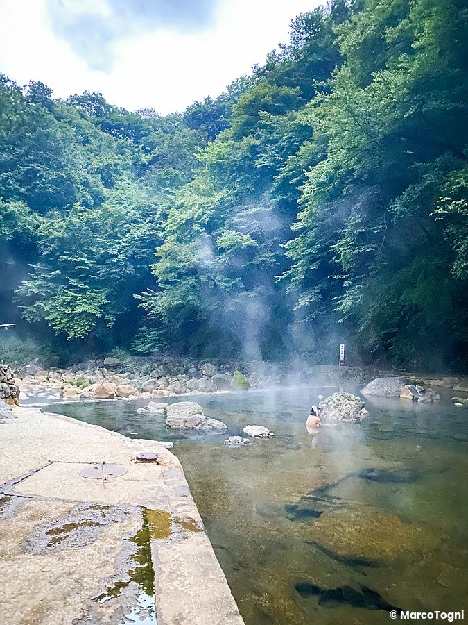 Shiriyaki Onsen, una onsen naturale con acqua calda tra le rocce e vegetazione.