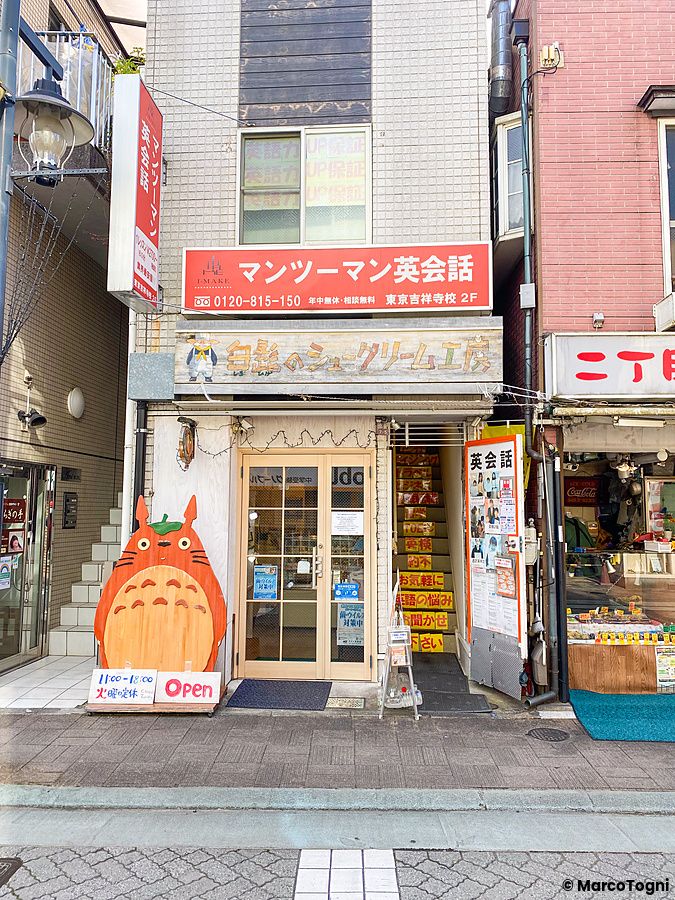 Facciata esterna di Shirohige’s Cream Puff Factory a Kichijoji con una decorazione in legno di Totoro davanti all'ingresso.