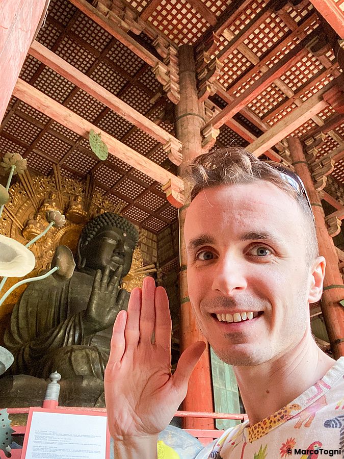 Marco Togni che saluta davanti alla statua del Buddha nel tempio Todaiji a Nara.