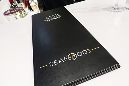 Il menù nero di Caviar House & Prunier posato su un tavolo bianco all'interno di uno dei loro bar a Tokyo.