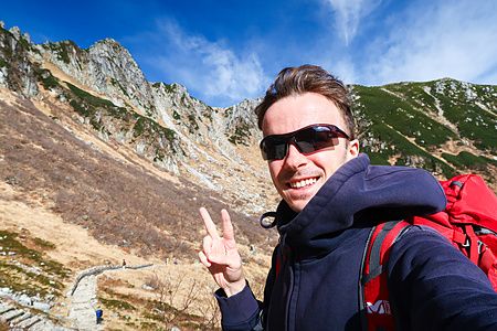 Marco Togni fa il segno di vittoria in un selfie con il panorama montuoso del Monte Kisokoma sullo sfondo.