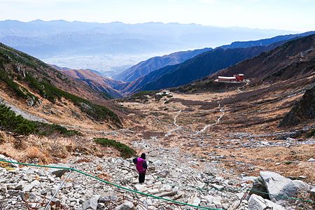 Una persona con uno zaino percorre un sentiero roccioso sul Monte Kisokoma, nelle Alpi Centrali di Nagano.