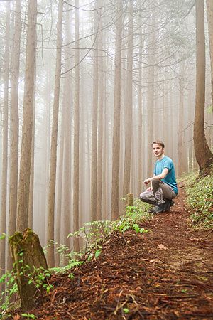 Persona accovacciata in una foresta nebbiosa sul Monte Mitake.