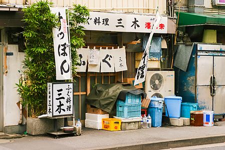 Facciata di un ristorante tradizionale tokyo a Tokyo con insegne in carta, tende noren e contenitori di plastica.