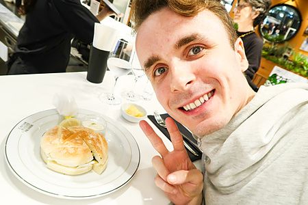 Marco Togni sorridente posa accanto a un sanwich costosissimo con caviale servito presso Caviar House & Prunier a Tokyo.