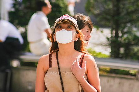 Donna con mascherina e cappellino a Shibuya, Tokyo.