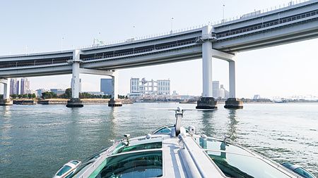 Veduta frontale dell'Hotaluna che naviga verso il Rainbow Bridge e l'edificio della Fuji TV nella baia di Tokyo.