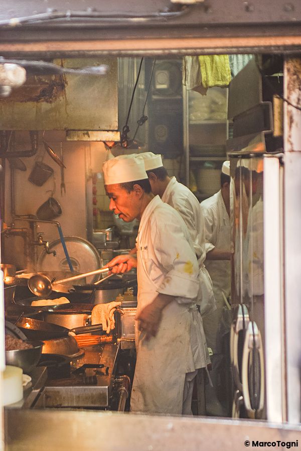 Due cuochi in divisa bianca lavorano all'interno di una cucina professionale in Giappone.