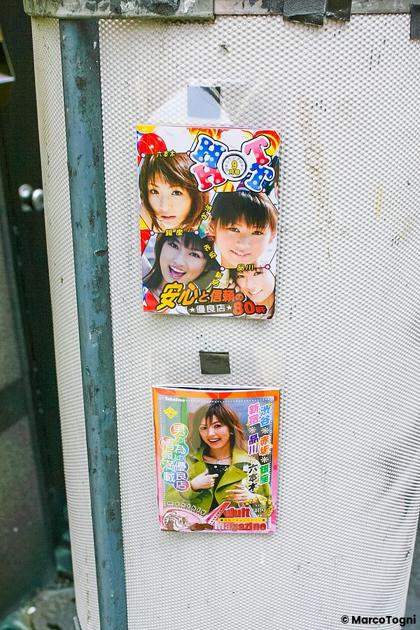 Libricini pubblicitari di servizi per adulti attaccati a un pannello a Tokyo.
