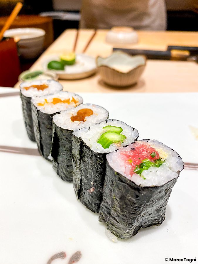 Una fila di maki sushi di diverse varietà posizionati su un vassoio bianco al ristorante Ginza Kyubey.